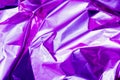 Neon crumpled holographic abstraction in bright pink and purple, selective focus, blur