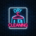 Neon dry cleaners glowing sign with hanger and shirt on a dark brick wall background. Cleaning service signboard Royalty Free Stock Photo