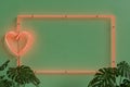 Neon frame with a heart on green wall with plants Royalty Free Stock Photo