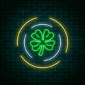 Neon glowing clover leaf sign in circle frames on a dark brick wall background. Green shamrock Royalty Free Stock Photo