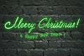 Neon green greeting lettering Merry Christmas and Happy New Year on black brick wall, neon lettering Royalty Free Stock Photo