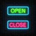 Neon green open and red close glowing signs in geometric shape on a brick wall background. Royalty Free Stock Photo