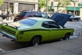 Neon green vintage car parked at the side of the road with an open hood showing the car engine