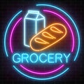 Neon grocery store glowing sign on a brick wall background. Food shop signboard with bread and milk in a circle frame.