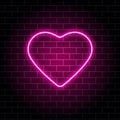 Neon heart. Bright night neon signboard on brick wall background with backlight. Retro pink neon heart sign. Design element for