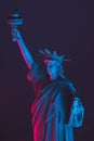 Neon illuminated Statue of Liberty on a dark background.