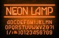 Neon Lamp alphabet font. Orange neon light letters, numbers and symbols. Brick wall background.