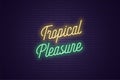 Neon lettering of Tropical Pleasure. Glowing text