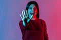 Neon light portrait of scared crazy woman standing with outstretched hand, showing stop gesture and screaming Royalty Free Stock Photo