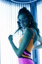 Neon light and sexy hipster girl. Young beautiful athletic woman model in a stylish color swimsuit in vintage sunglasses with