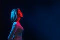 The neon lights of the club. Portrait of a young woman posing in profile. Blue and red light. Black background. Copy space Royalty Free Stock Photo