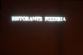 Neon lights inscription in Italian saying pizza restaurant or pizzeria.