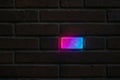Neon-lit brick glowing pink and blue in dark wall, symbolizing individuality and contrast in uniform structure Royalty Free Stock Photo