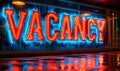 Neon-lit VACANCY sign in bold 3D letters on a reflective blue surface indicating available employment opportunities or Royalty Free Stock Photo