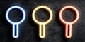 Neon magnifying glasses in blue, yellow, and red on dark background Royalty Free Stock Photo