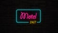 Neon Motel 24/7 sign glows and lights on grunge brick wall.