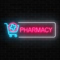 Neon pharmacy glowing signboard with medical cross in shopping cart on brick wall background. Royalty Free Stock Photo