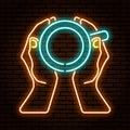 Neon sign. Hands holding a cup top view. Against the background of a brick wall.