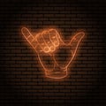 Neon sign with an orange glow. Hand gesture, shaka. little finger and thumb.