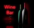 A neon sign spells Wine Bar with bottles of wine and a glass of wine in the foreground Royalty Free Stock Photo