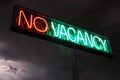 Neon Sign stating No Vacancy in red and green with storm clouds Royalty Free Stock Photo