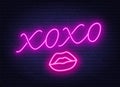 Neon sign xoxo with a kiss on a dark background.