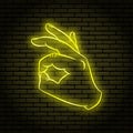 Neon sign with a yellow glow. Hand gesture, shows OK.