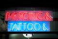 Neon signboard with Piercing & Tattoo at night. Royalty Free Stock Photo