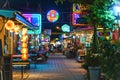 Neon signs and vibrant lights illuminating the night market stalls