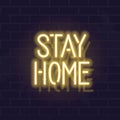 Neon stay home typography. Glowing vector motivation typography. Fluorescent letters on dark brick wall background.