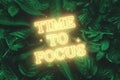 Neon yellow inscription: time to focus, on a green natural background. Concept for motivating background, business, self-