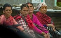 CLOSE UP: Four serious local women sit and look around the village in Nepal.