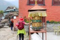 Woman rotates a colorful prayer wheel in Nepal