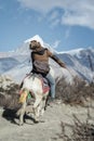 Nepalese man riding fast on a small horse on the trail from Manang to Thorong La Pass.