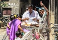 A Nepalese man street seller sells fruit tomatoes from a bicycle and weighs goods to buyers on the scales