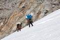 Nepalese Mountain Porters climbing Glacier carrying heavy Luggage