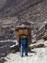 Nepalese porter carrying a heavy load to the pass Royalty Free Stock Photo