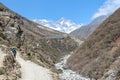 Nepalese porter walks on footpath. Everest mountain in the background.
