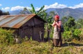 Nepalese woman in traditional clothes greeting namaste next to her small house