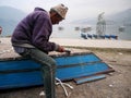 Nepali old man carpenter or repairman senior nepalese people working repair wooden boat beside of Phewa Tal or Fewa Freshwater