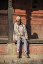 A Nepali senior gentleman sits on step , Nepal Royalty Free Stock Photo