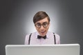 Nerd at the computer. Young nerd man working at the computer while isolated on grey Royalty Free Stock Photo