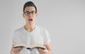 Nerd with glasses and a white t-shirt is reading a book on a white background Royalty Free Stock Photo