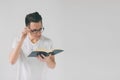 Nerd with glasses and a white t-shirt is reading a book on a white background Royalty Free Stock Photo