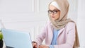 Nerd muslim woman in hijab is working on a graduation bachelor project typing on laptop