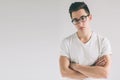 Portrait of young Nerd man wearing glasses and t-shirt standing with crossed arms and on white background while looking Royalty Free Stock Photo