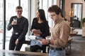 Nerdy looking guy stands in front of friends. Group of students in eyewear standing in the learning room with documents