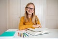 Nerdy teenage girl wearing glasses sitting at her desk with open book Royalty Free Stock Photo