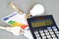 Nergy efficiency rating table with light bulbs, calculator and powercord on grey background, close-up. Concept for Energy price Royalty Free Stock Photo