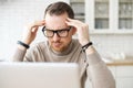 Nervous business man sitting at laptop holding hands to temples Royalty Free Stock Photo